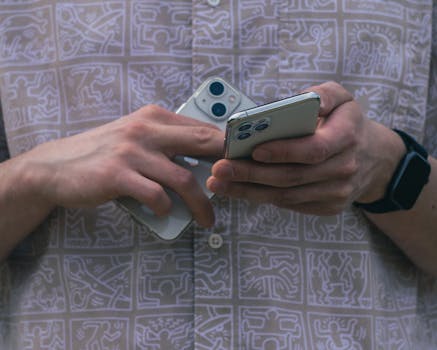 Detail of hands holding two smartphones, showcasing modern technology usage.