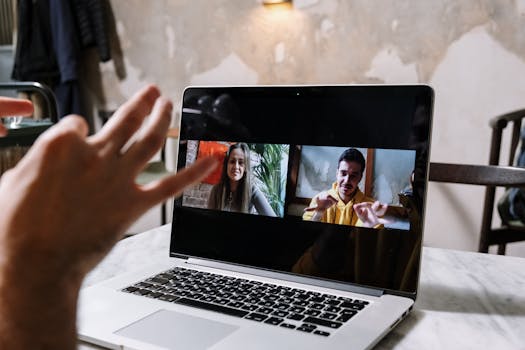 Hands gesturing during a video call on a laptop screen, showing two people in a virtual meeting.