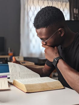 Young man deeply engaged in reading a book at home, fostering knowledge and wisdom.