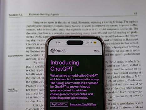 Smartphone showing OpenAI ChatGPT in focus, on top of an open book, highlighting technology and learning.